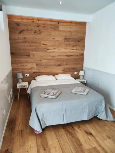 een slaapkamer met een groot bed en een houten muur bij Ak holidays apartments 81 in Bologna