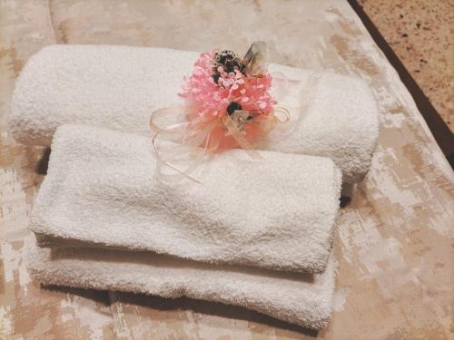 a pile of towels on a table with a bouquet of flowers at B&B Rosa dei Venti in Sorso