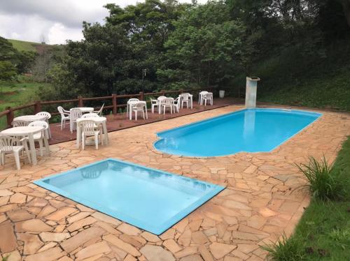 uma piscina com cadeiras e uma mesa em Reserva Provenzano Villas em Itatiba