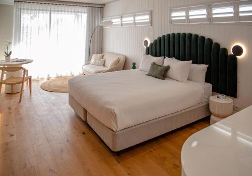 a bedroom with a large bed with a large green headboard at Essence Peregian Beach in Peregian Beach