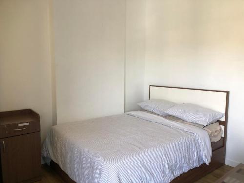 Schlafzimmer mit einem Bett mit weißer Bettwäsche und einer Kommode in der Unterkunft Antara Residential Condominium in Talisay