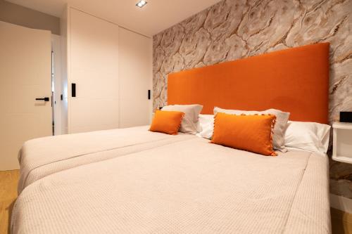 a bedroom with a large bed with an orange headboard at Apartamento Illa do Santo in Bueu