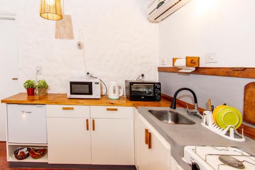 cocina blanca con fregadero y microondas en Lo De Sara en Yerba Buena
