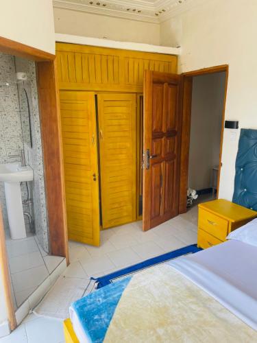 a room with a bed and wooden doors and a sink at Residence SVET in Kribi