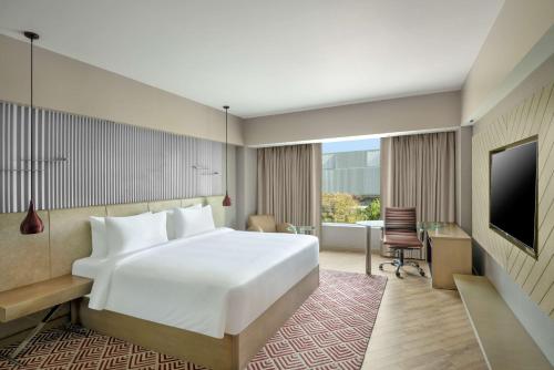 グルガオンにあるカントリー イン＆スイーツ バイ ラディソン グルグラム セクター29のベッド、デスク、テレビが備わるホテルルームです。