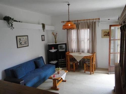 uma sala de estar com um sofá azul e uma mesa em Paradise Inn em Milatos