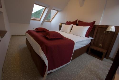 a bedroom with a large bed with red and white pillows at Hotel Gott in Braşov