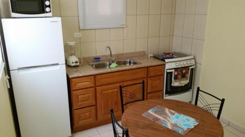 een keuken met een tafel en een witte koelkast bij Paramira Apartment in Oranjestad