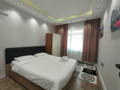 Un dormitorio con una gran cama blanca y una ventana en Tekin Suit, en Bandırma