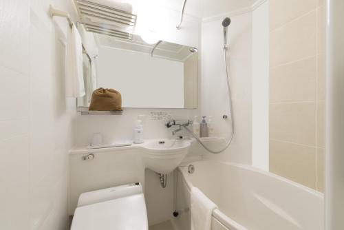 a white bathroom with a sink and a toilet and a tub at HOTEL Guest1 Ueno Ekimae in Tokyo