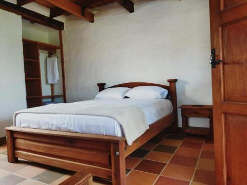 a bedroom with a wooden bed with two pillows at cabaña 3 palos in Barichara