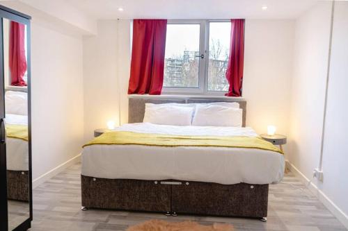 1 dormitorio con 1 cama grande y cortinas rojas en Pristine Relocation Apartments en Londres