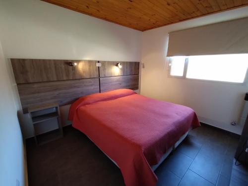 アルミネにあるAluminé Cabañasのベッドルーム(赤いベッド1台、デスク付)