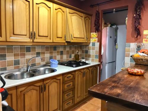 una cocina con armarios de madera y fregadero en Casa el Acebuche, en Cazorla