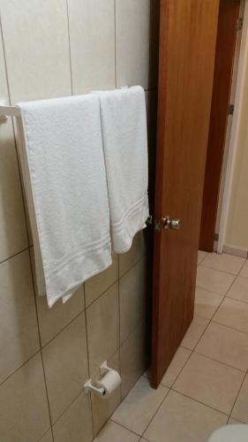y baño con toallas blancas colgadas en una cabina de ducha. en Paramira Apartment, en Oranjestad