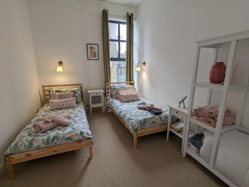 a bedroom with two beds and a book shelf at Camberwell Church Street in London