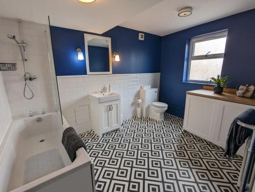 ein blaues Badezimmer mit einer Badewanne, einem WC und einem Waschbecken in der Unterkunft Camberwell Church Street in London