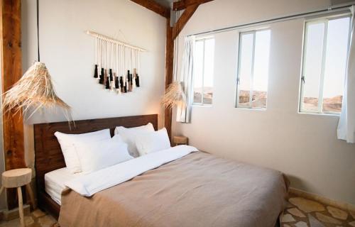 Schlafzimmer mit einem Bett mit weißer Bettwäsche und Fenstern in der Unterkunft Selina Tzukim - Soft opening - סלינה צוקים in Tsukim
