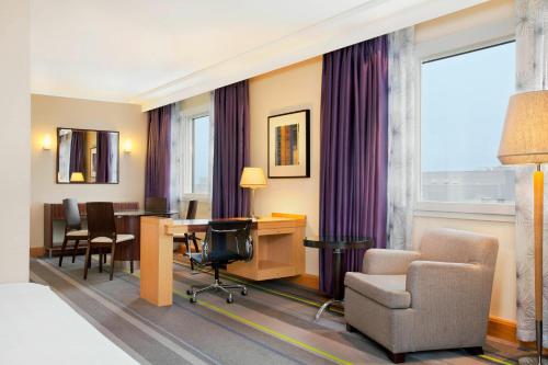 a hotel room with a desk and chairs and a table at Sheraton Brussels Airport Hotel in Zaventem