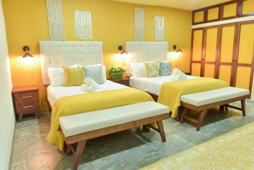 two beds in a room with yellow walls at K an nah Diseño tropical inspirado en el jaguar in Mérida
