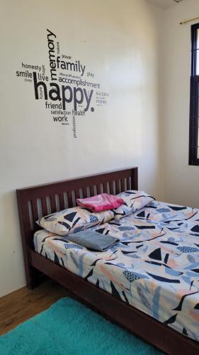 a bedroom with a bed with a happy sign on the wall at Camilyn Home Stay in General Trias