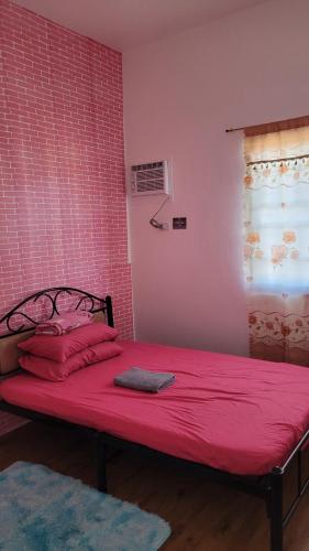 a bed in a room with red sheets and a window at Camilyn Home Stay in General Trias