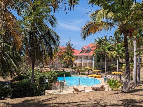 un complexe avec une piscine et des palmiers dans l'établissement Le Laïlana, à Sainte-Anne