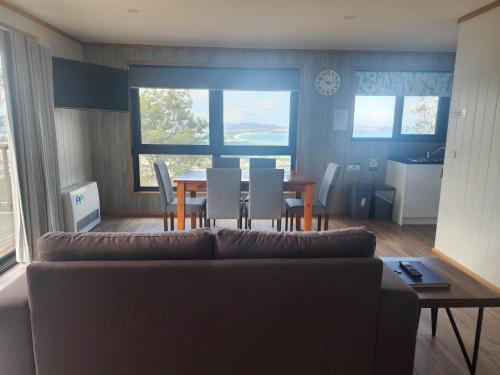a living room with a couch and a table and chairs at Mount Rumney Escapes - 5 Seaview Kangaroo House in Mount Rumney