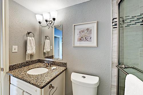 ein Badezimmer mit einem Waschbecken, einem WC und einem Spiegel in der Unterkunft Inverness #304 in South Padre Island