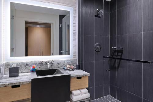 a bathroom with a sink and a shower with a mirror at Art Ovation Hotel, Autograph Collection in Sarasota