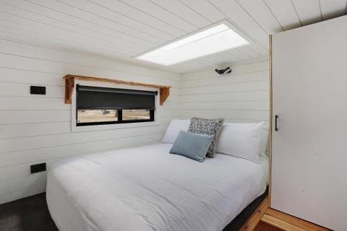 a bedroom in a tiny house with a bed and a window at Boydtown Beach Holiday Park in Eden