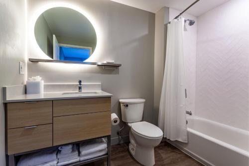 a bathroom with a toilet and a sink and a mirror at TownePlace Suites by Marriott Raleigh - University Area in Raleigh