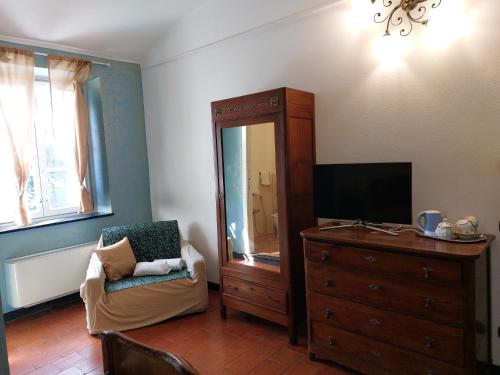 uma sala de estar com uma cómoda, uma televisão e uma cadeira em Nonna Litta em Albenga