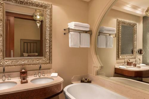 a bathroom with two sinks and a tub and a mirror at Ajman Saray, a Luxury Collection Resort, Ajman in Ajman 