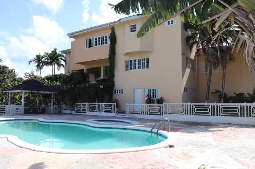 a villa with a swimming pool in front of a building at CCBS Paradise Jamaica in Runaway Bay