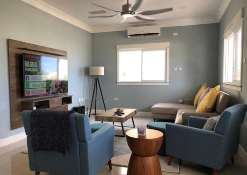 a living room with two blue couches and a tv at CCBS Paradise Jamaica in Runaway Bay