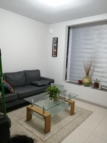 uma sala de estar com um sofá e uma mesa de café em vidro em Habitación Bosquemar em Puerto Montt