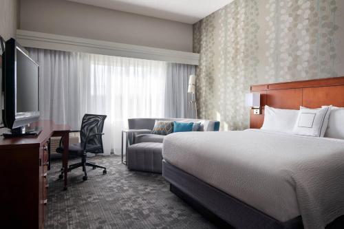 ミルピータスにあるCourtyard Milpitas Silicon Valleyのベッド、デスク、ソファが備わるホテルルームです。