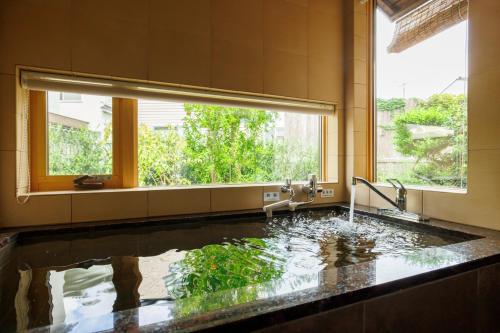 een badkamer met een groot zwembad met water bij Machi no Odoriba in Kanazawa