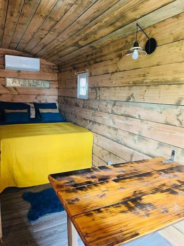 een slaapkamer met een geel bed en een houten muur bij Roulotte À Tahiti in Punaauia