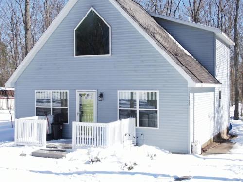 a blue house with a white fence in the snow at *4BR 2BA N Shore Hidden Retreat* in Roscommon