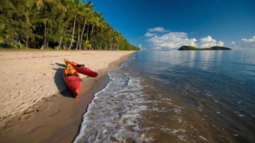 a red kayak sitting on the shore of a beach at Parkview - Palm Cove in Palm Cove