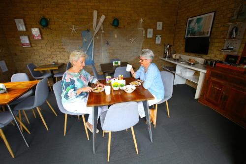 Dos mujeres mayores sentadas en una mesa comiendo comida en Tweed Harbour Motor Inn, en Tweed Heads