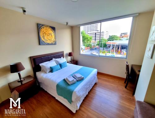 a bedroom with a bed and a large window at Margarita Apartamentos in Cochabamba