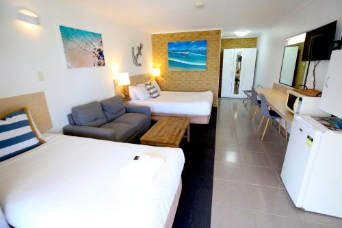 um quarto de hotel com uma cama e um sofá em Tweed Harbour Motor Inn em Tweed Heads