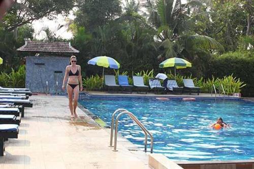 a woman in a bathing suit standing next to a swimming pool at Cherai Beach Resorts in Cherai Beach