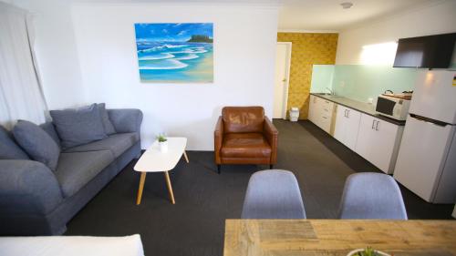 a living room with a couch and a table and a kitchen at Tweed Harbour Motor Inn in Tweed Heads