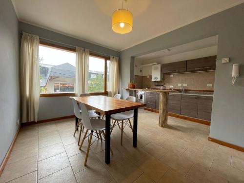 cocina con mesa de madera y sillas blancas en Frambuesas Flat en Villa La Angostura