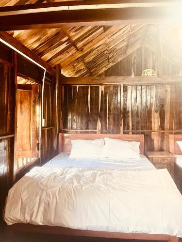 Bett in einem Zimmer mit Holzwänden in der Unterkunft Thông Garden - Lộc Đức in Bảo Lộc