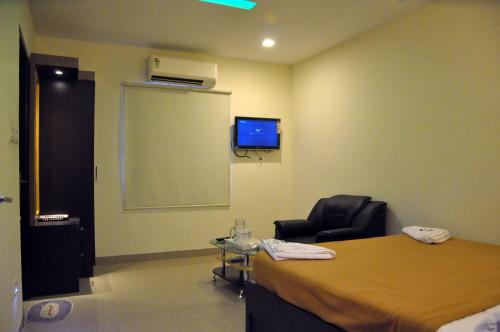 a room with a bed and a chair and a screen at Hotel Metro in Kumbakonam